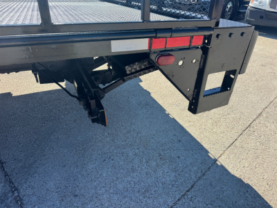 Isuzu NPR-HD rear/underbody showing flatbed equipment, hitch area, and bumper with rectangular cutouts and lights.