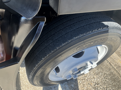 Isuzu NPR-HD truck wheel and fender close-up showing tire and wheel hub with lug nuts.
