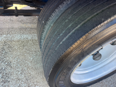 Isuzu NPR-HD truck wheel/tire and part of flatbed chassis showing dual rear tires and wheel with silver rim.