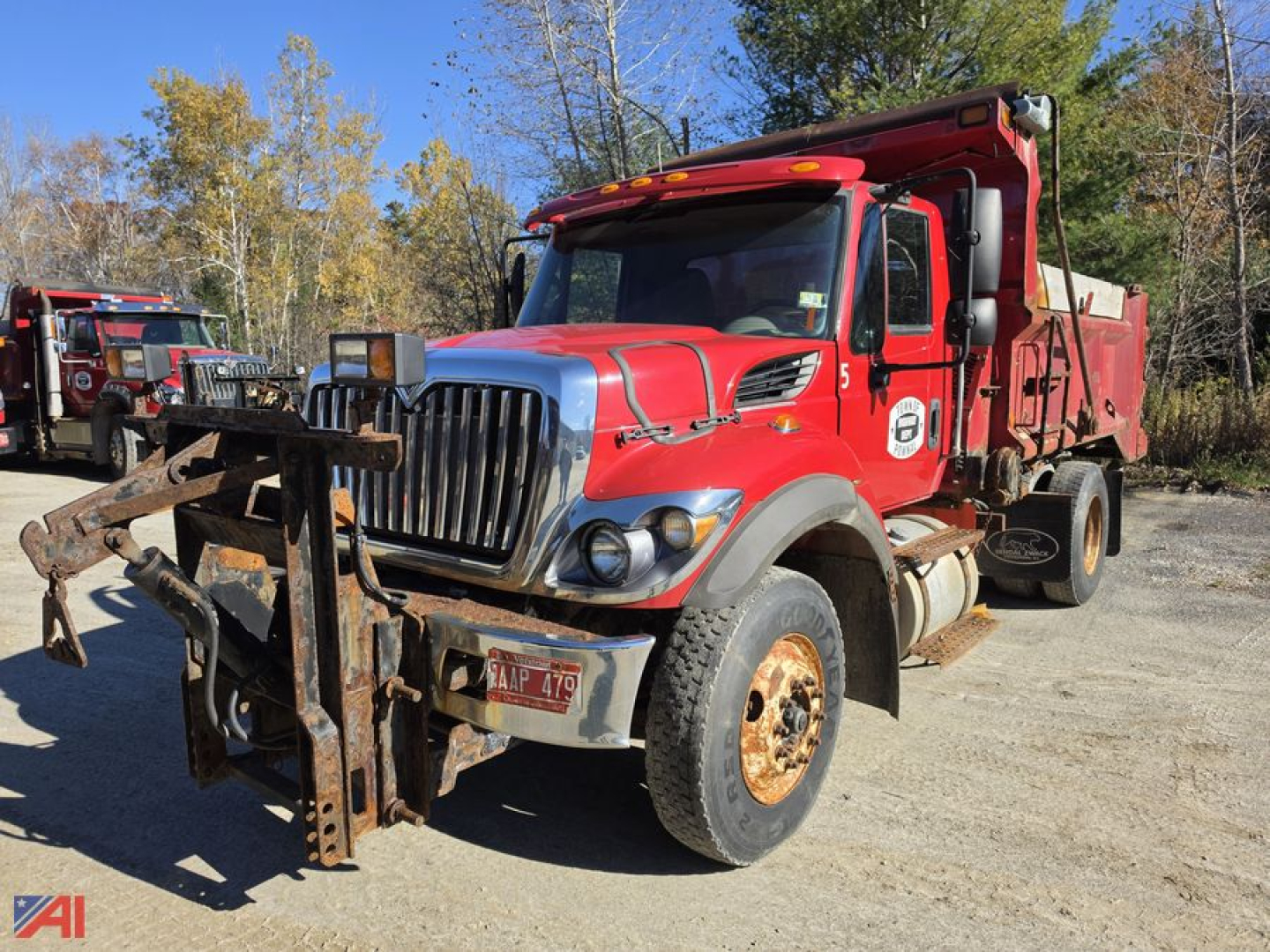Dump truck 2015 International WorkStar 7400 with front plow and dump bed, red cab, rusty front bumper and wheel wells, VIN visible on plate.