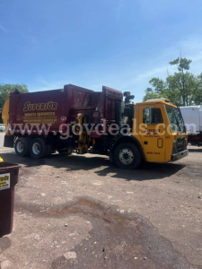 Truck cab and refuse body in-service showing Superior Waste Services lettering on the side of a yellow Mack LEU600 cab and maroon refuse body.