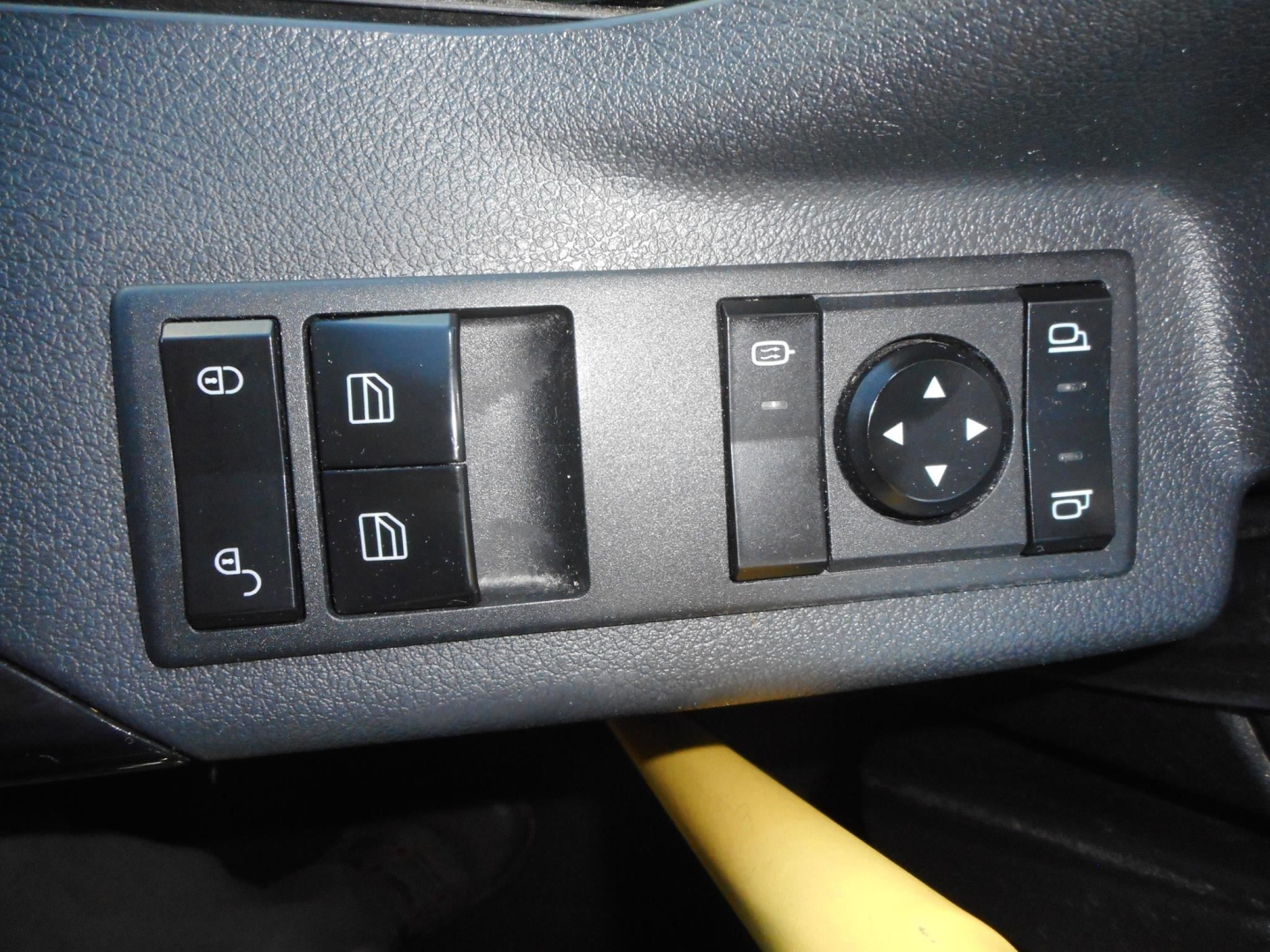 Cab interior control panel showing window/ mirror controls and joystick-like dial for adjustment.