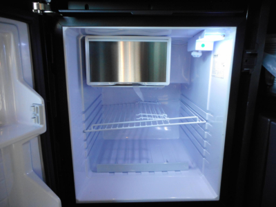 Freightliner Cascadia 126 sleeper cab interior small fridge or freezer with open empty shelves and a mounted screen.