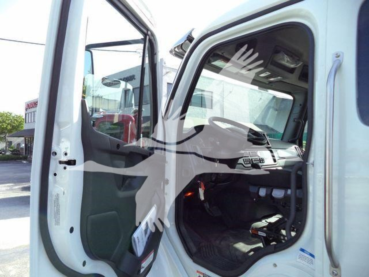 Cab view of Freightliner Business Class M2 106 truck with open door showing interior dashboard and steering wheel.
