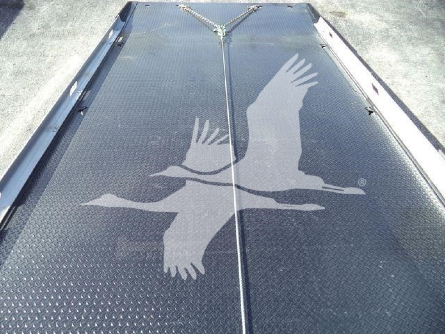 Flatbed or deck area of a Freightliner Business Class M2 106 with a large white bird logo on a textured metal surface, no visible text besides logo.