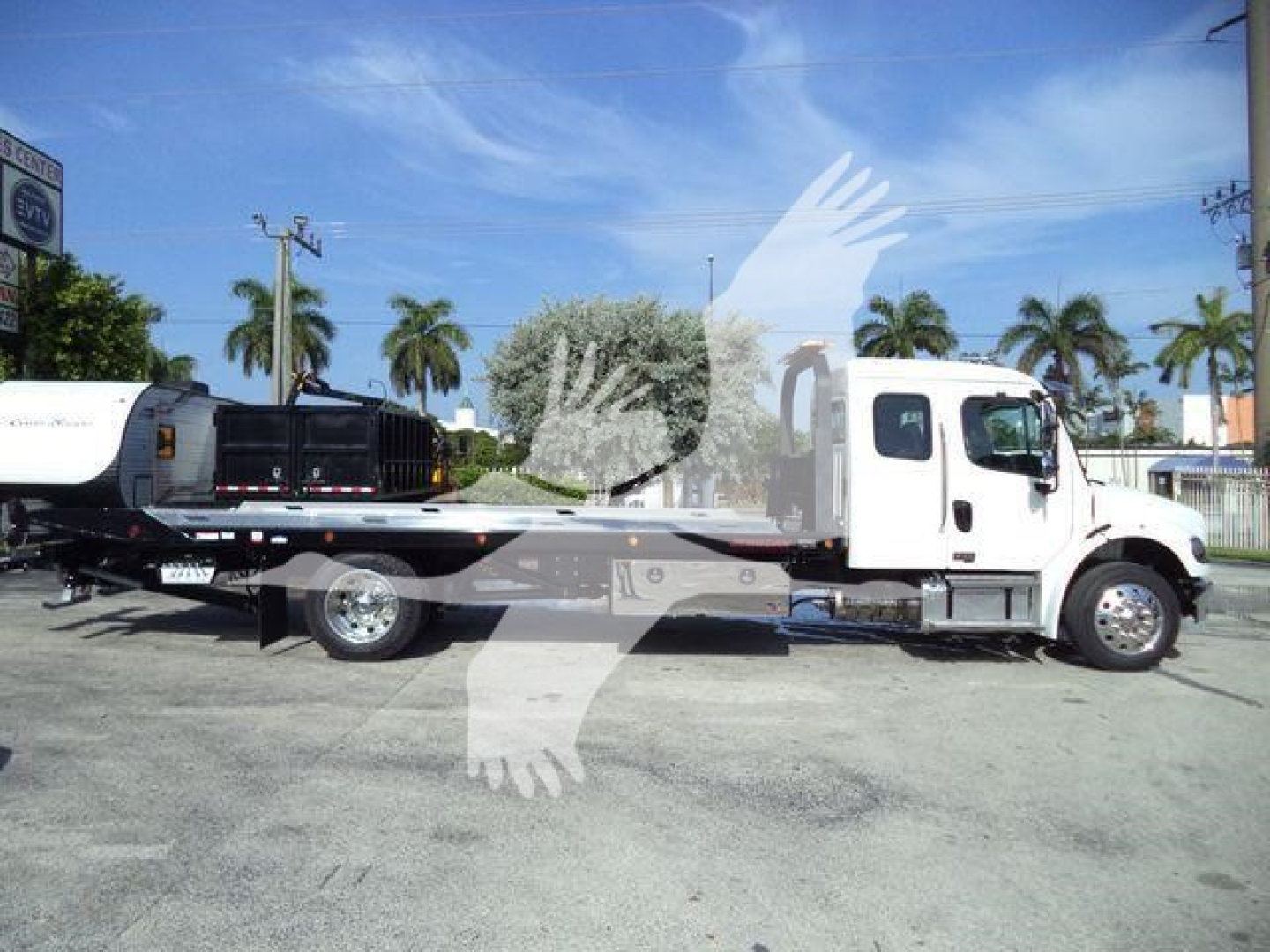 Freightliner Business Class M2 106 rollback tow truck in side view with long flatbed and white cab.