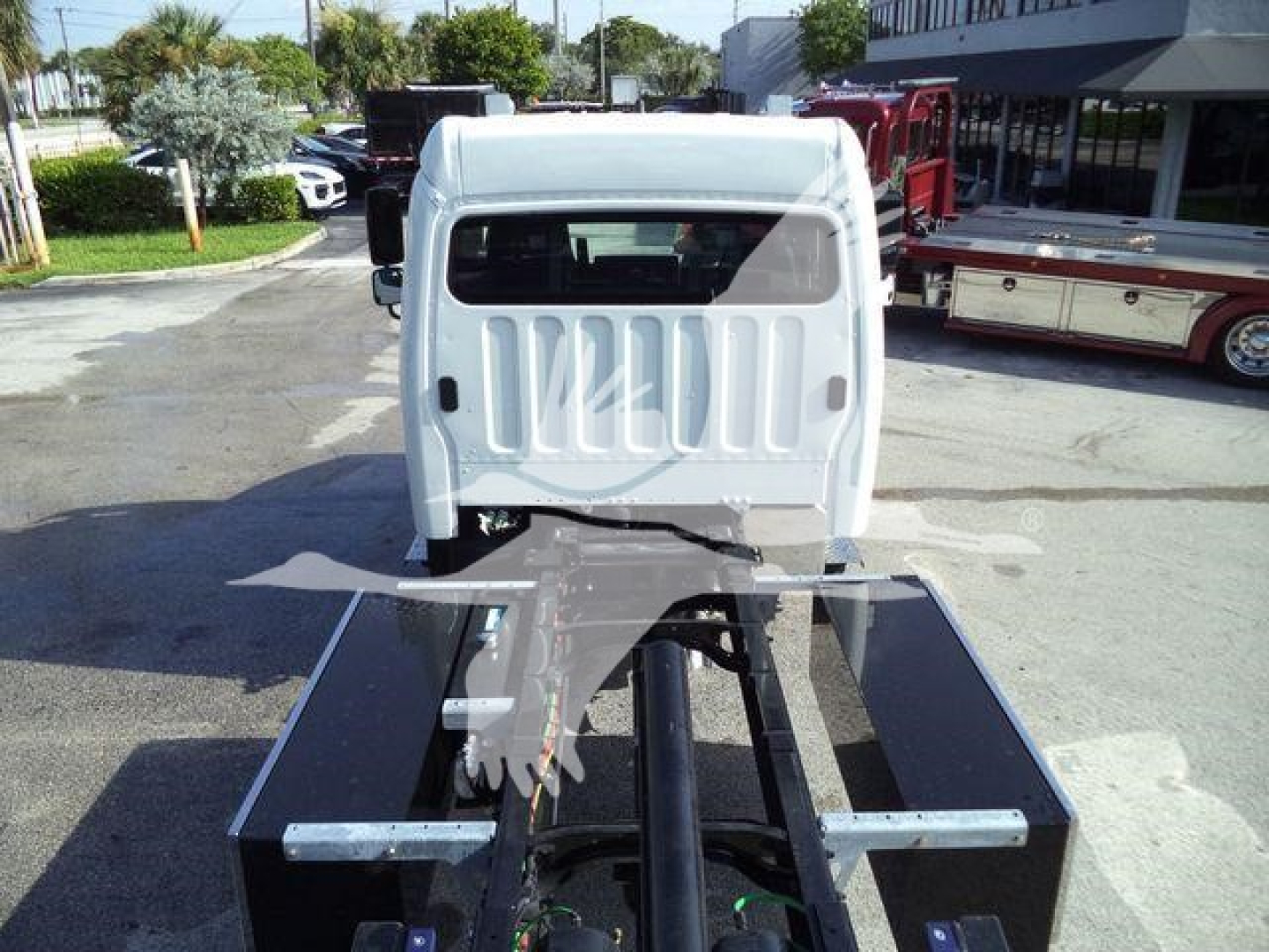 Truck cab rear view showing chassis and fifth-wheel area for Freightliner M2-106 rollback configuration with raised cabin window.