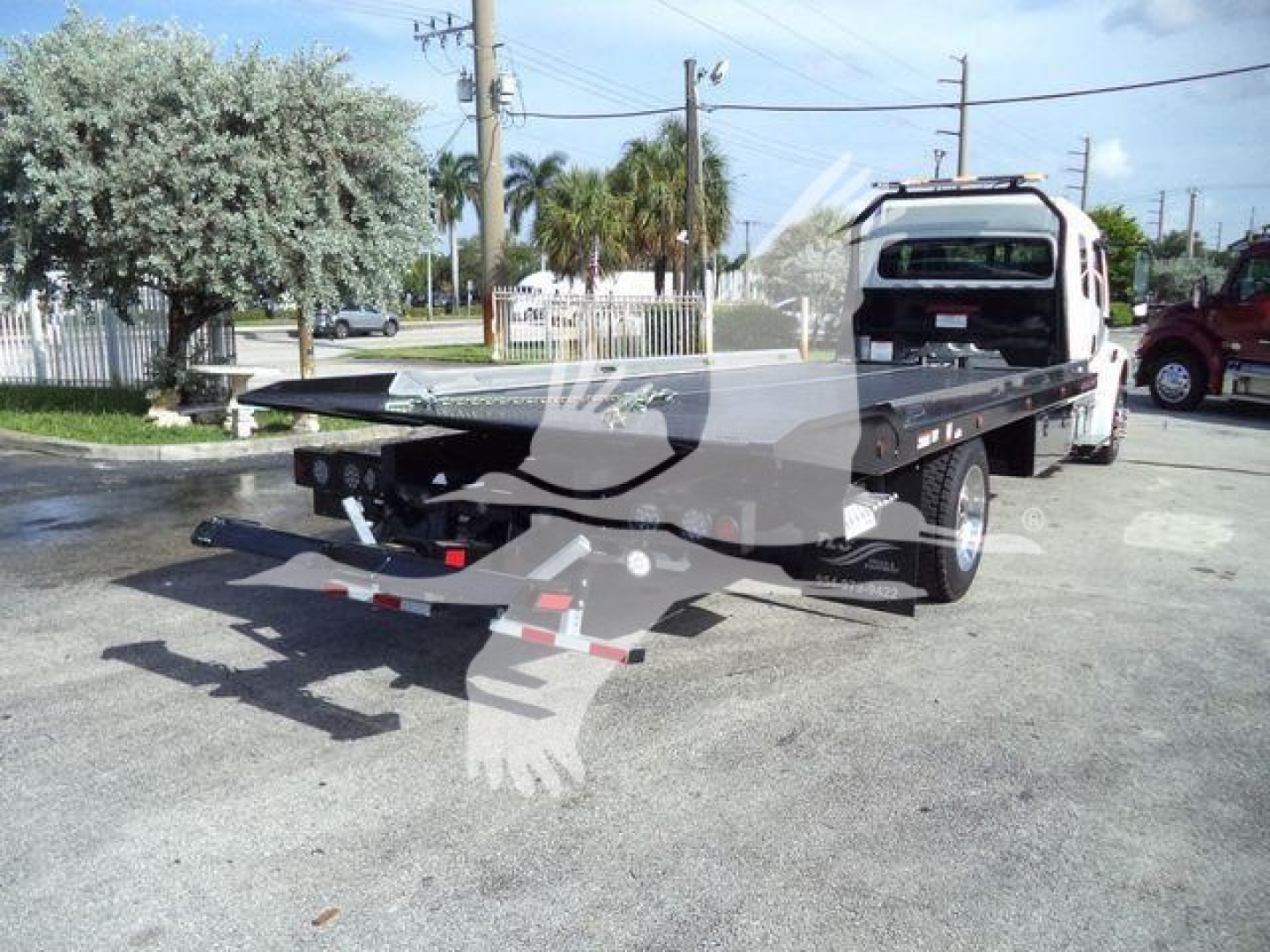 Freightliner Business Class M2 106 rollback truck with flatbed at rear and tow equipment visible.