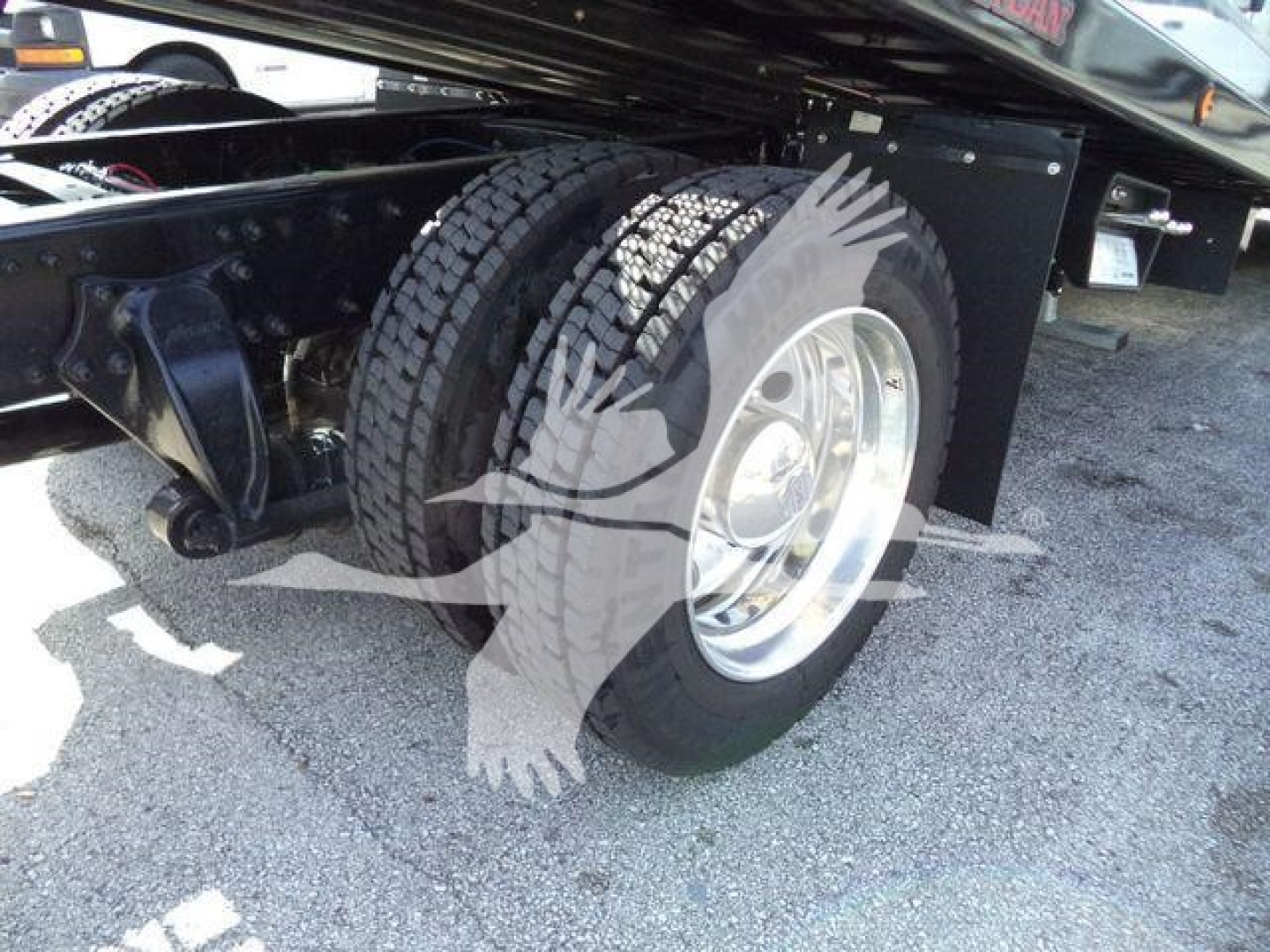 Freightliner Business Class M2 106 rollback truck rear wheel and dual tires visible under chassis with steel wheels and black undercarriage.