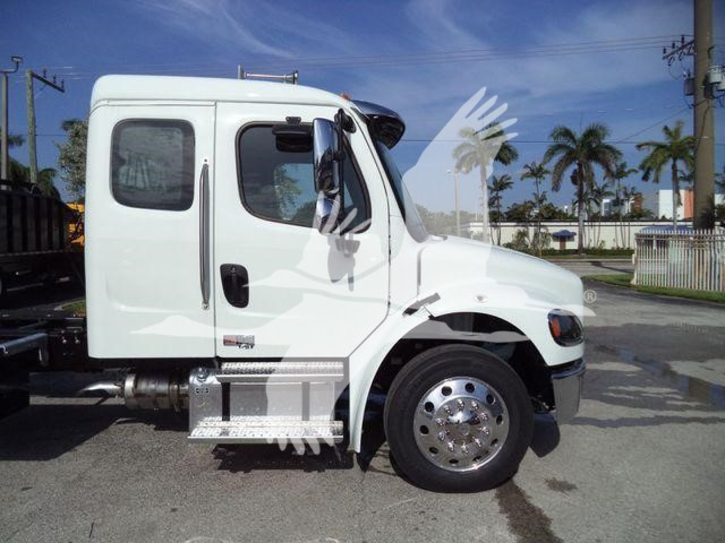 Truck side view of a white Freightliner Business Class M2 106 cab with chrome wheel covers and side steps.