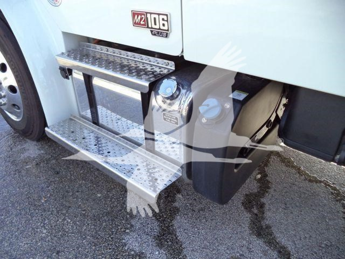 Freightliner M2 106 side steps and entry cab area with metal perforated steps and fuel tank behind.