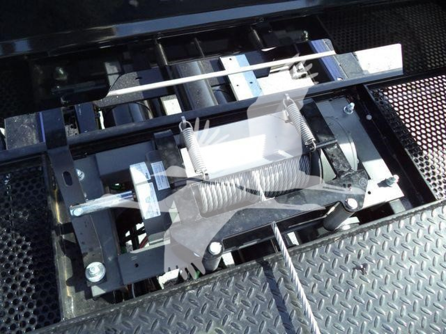 Freightliner M2 106 rollback showing hydraulic tow/flatbed mechanism with metal levers and springs.