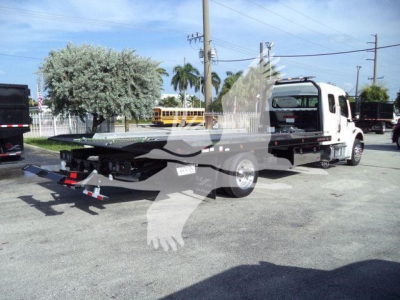 Freightliner Business Class M2 106 rollback truck with flatbed and tow hitch, side view.