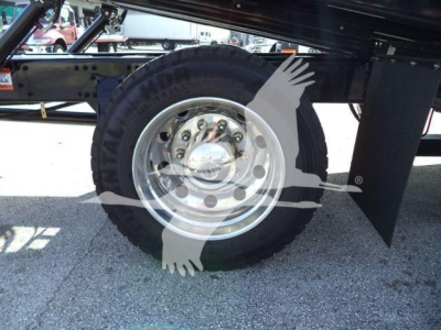Freightliner Business Class M2 106 wheel and suspension with chrome hubcap and tire, showing part of frame and a watermark overlay.