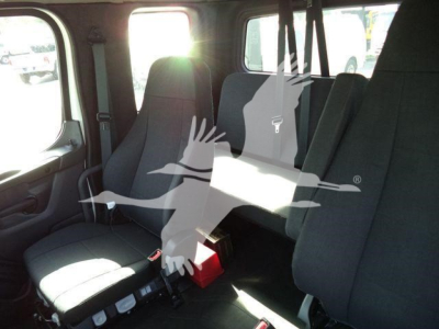 Freightliner M2 106 cab interior with seating for two and a folding jump seat, black fabric upholstery, daylight from window.