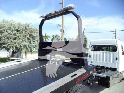 Freightliner M2 106 rollback truck bed with DPF area and hoist arch; visible upper beacon light and flat steel deck, JD5066 stock tag; white cab in background