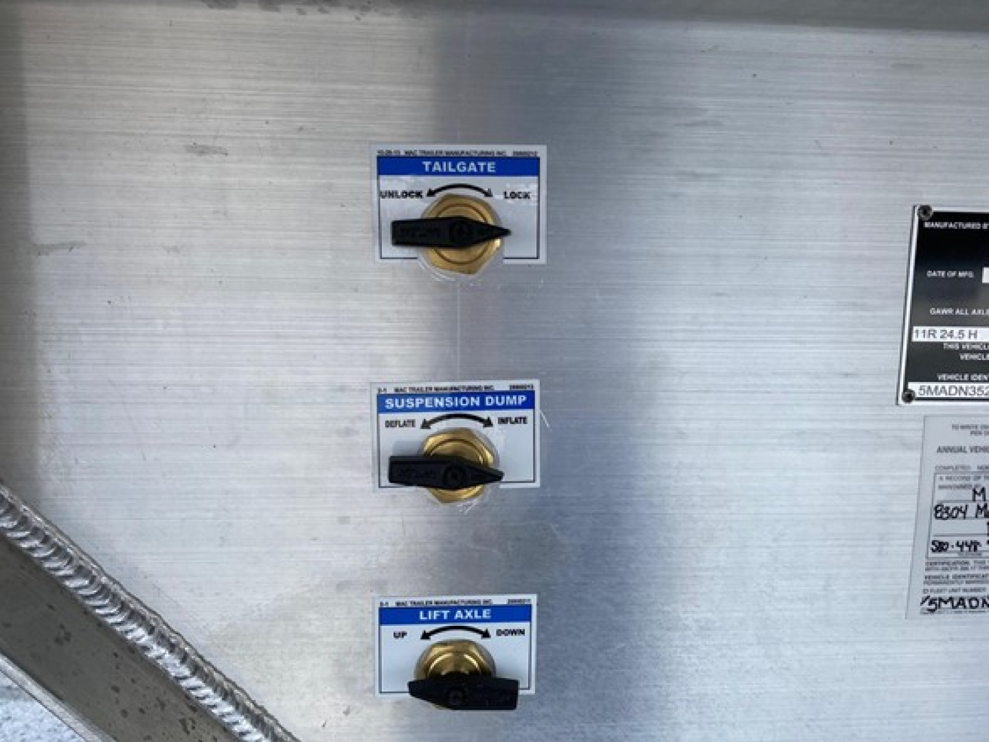 Trailer interior wall with three labeled dials: Tailgate, Suspension Dump, and Lift Axle controls in view.