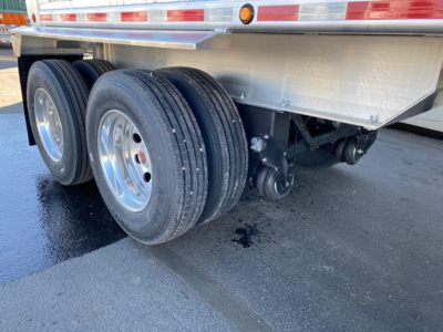 Triple axle trailer wheels and suspension underside of a Mac Western Lightweight dump trailer showing dual tire setup and undercarriage components.