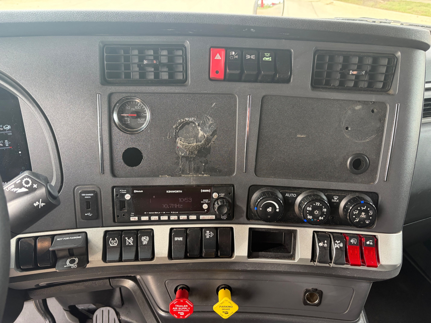 Kenworth T680 dash and instrument cluster with vents, switches, and controls; visible buttons and knobs on the dash; no brand markings legible beyond general truck interior.
