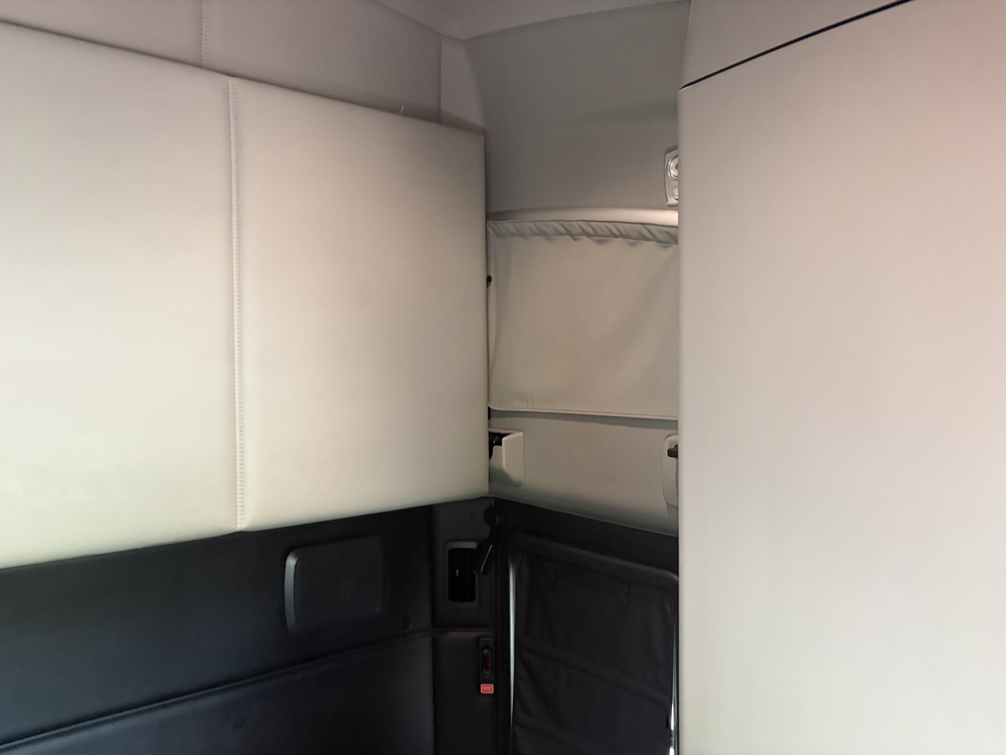 Interior cab space of a Kenworth T680 sleeper truck showing light gray sleeper walls and storage compartments.