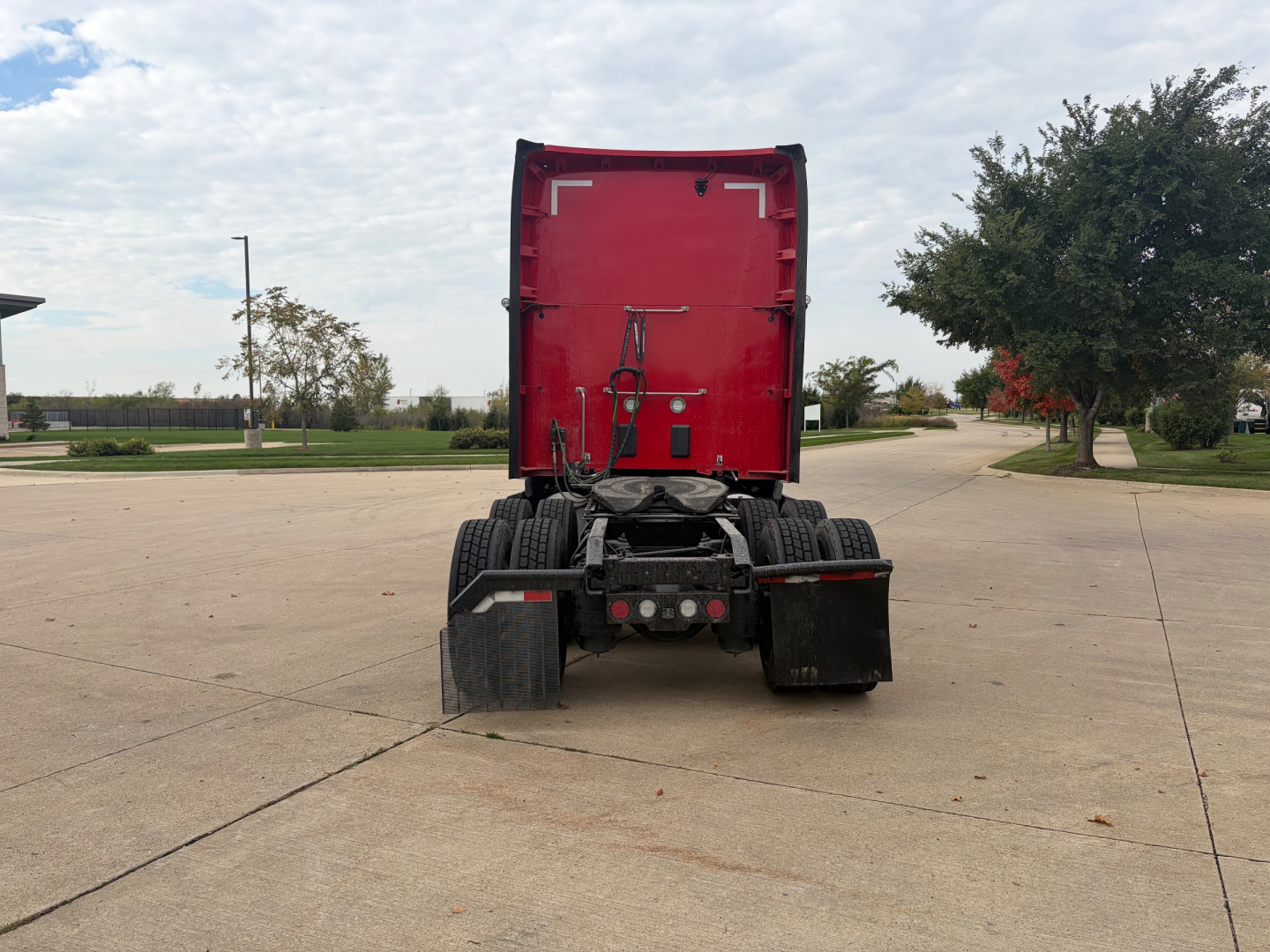 Kenworth T680 rear view showing fifth wheel and dual rear axles, red cab, trailer height clearance, clear sky.