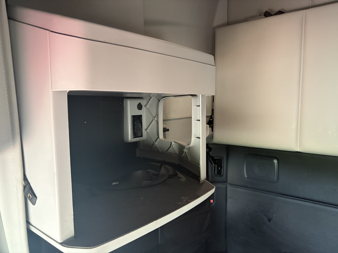 Kenworth T680 cabin interior showing open storage area under sleeper with dashboard and empty compartment