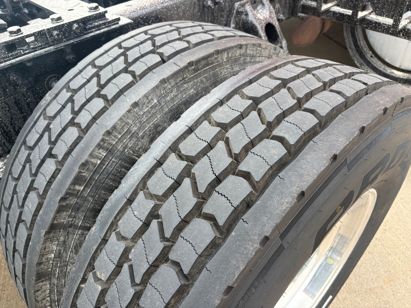 Kenworth T680 wheel and tire close-up showing tread pattern and dual rear axle area.