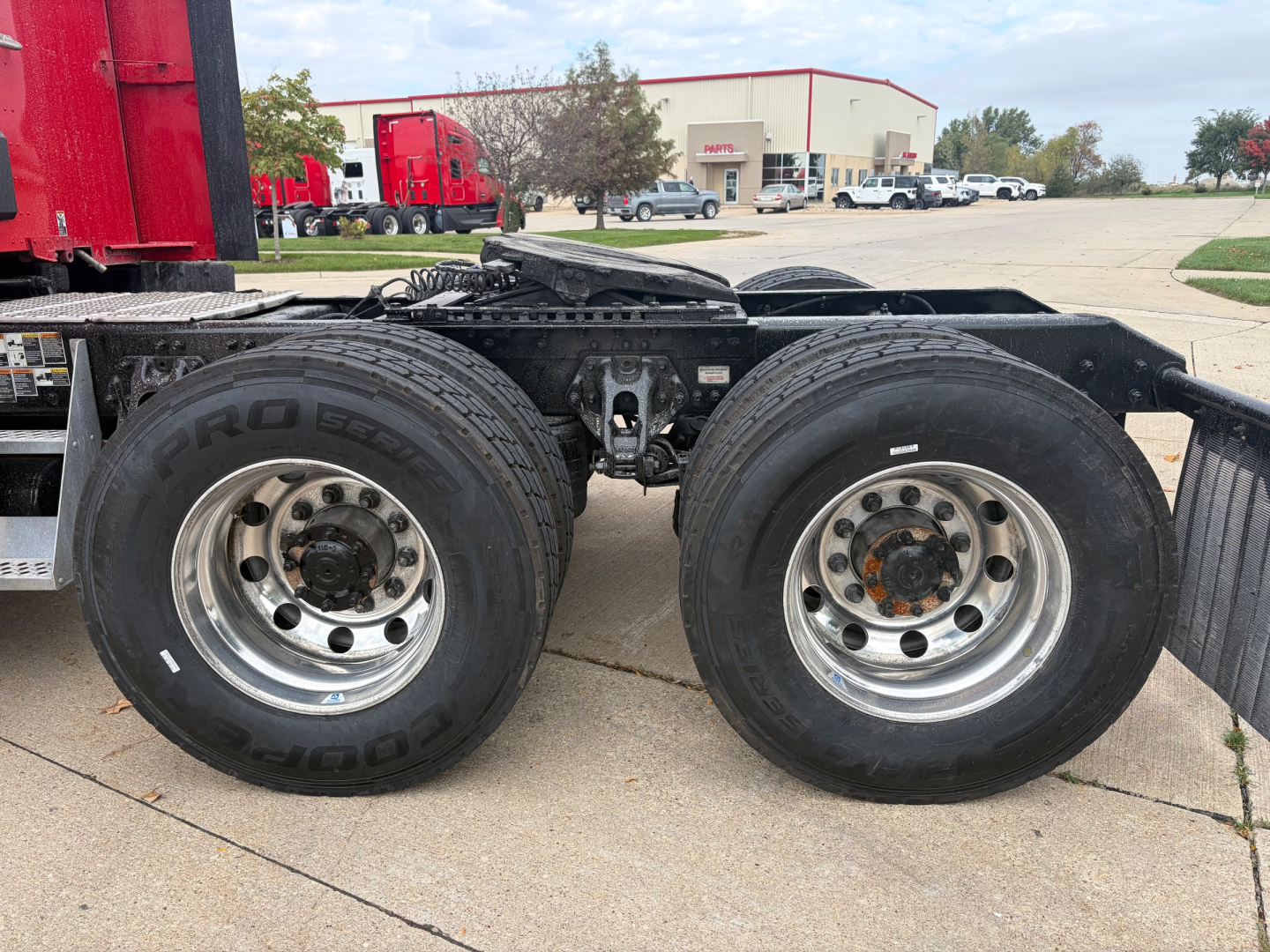 Kenworth T680 trailer axles with dual rear wheels and chrome rims showing tire brands and undercarriage components.