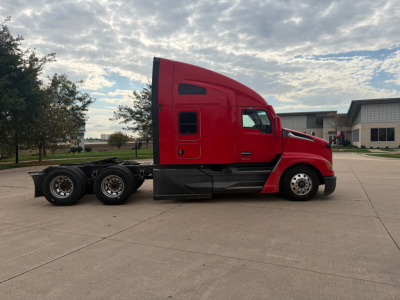 Red 2023 Kenworth T680 cab forward semi truck side profile, sleeper with stacked wheels on the rear and black undercarriage.