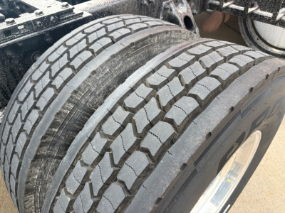 Kenworth T680 wheel and tire close-up showing tread pattern and dual rear axle area.