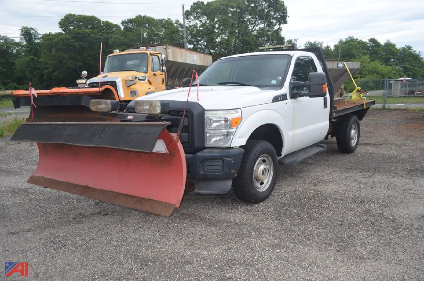 White 2011 Ford F250 Super Duty truck with a large red snow plow on the front and a flatbed equipped with a spreader plow apparatus.