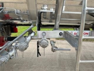 Trailer undercarriage showing plumbing manifolds, valves, and a gauge on a Dragon 8400 trailer. Visible components include pipework, fittings, and a circular hand valve.