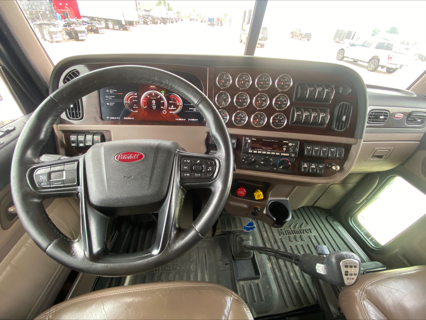 Peterbilt 389 truck interior showing steering wheel, instrument cluster, gear shifter, and dashboard controls in view.