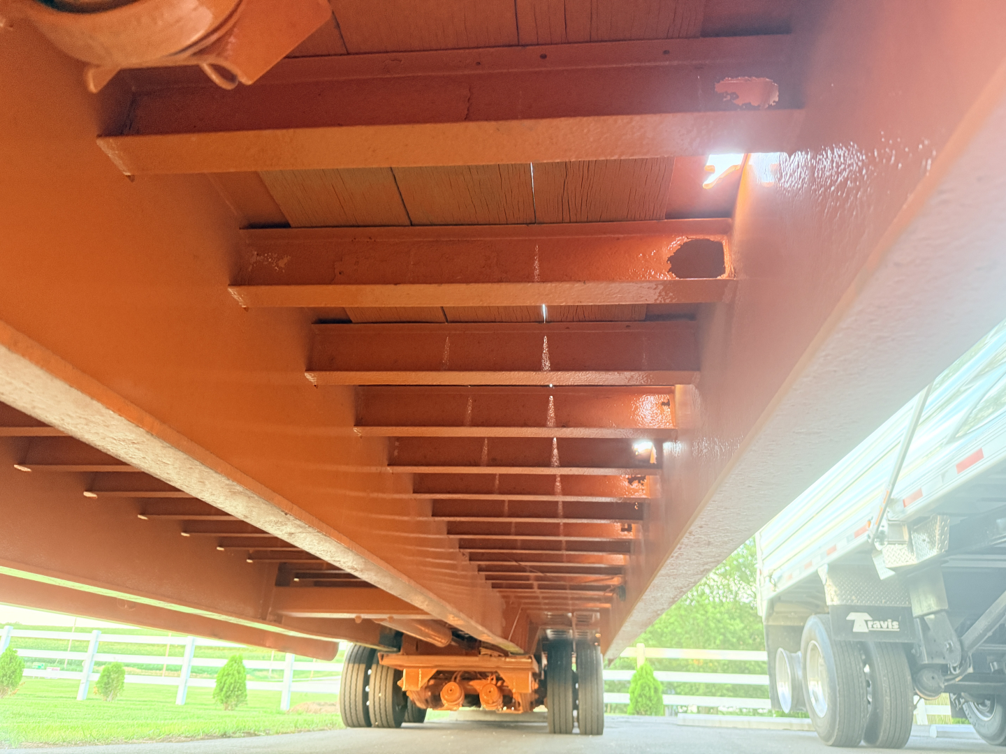 Traveling tail section of a Landoll lowboy trailer showing steel beams and suspension near wheels.