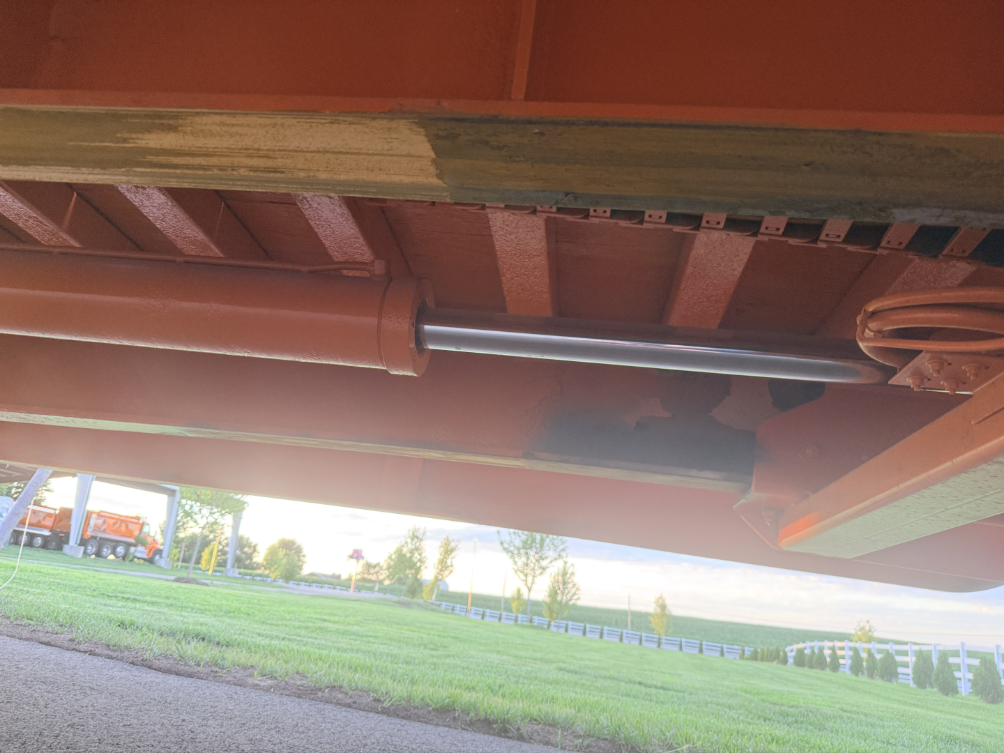 Rail/undercarriage view of a Landoll trailer showing a cylindrical cylinder/piston component under the frame and structural crossmembers.