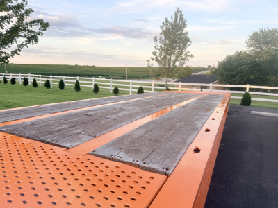 Orange Landoll trailer deck with wooden planks and perforated steel sections, outdoor lot in background.
