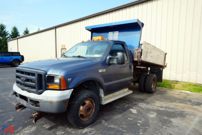 Ford F-350 XL SD dump truck in front view showing dual rear wheels and dump bed with blue tilting hopper.