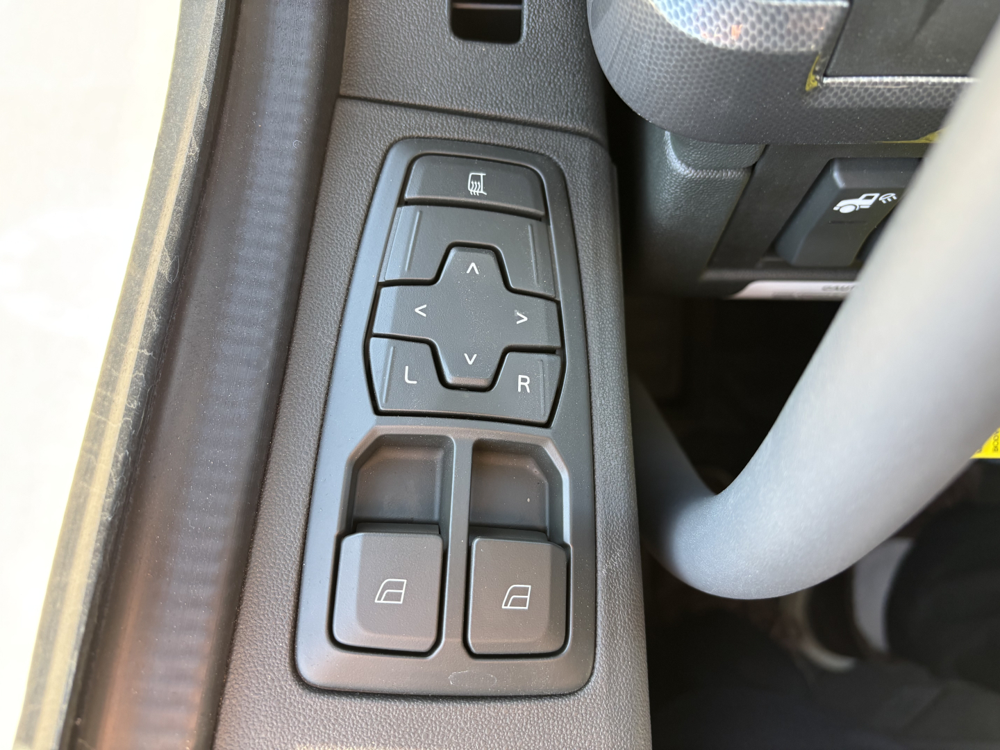 Door control panel in a Volvo truck interior with window lock and mirror adjustment buttons visible.