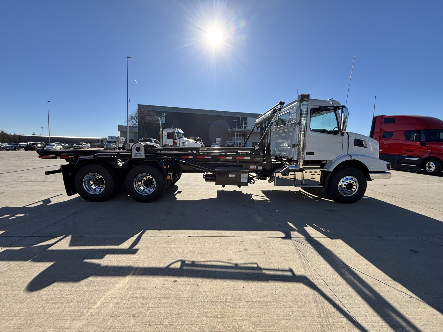 Volvo VHD64B300 rolloff truck side view showing chassis and cab with greenish-gray body, 6x4 configuration, dual rear axles, and hydraulic system.