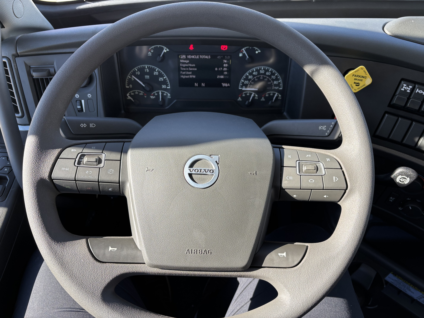 Volvo steering wheel and dashboard in-cab view of a Volvo VHD64B300 truck, with steering wheel controls and digital instrument cluster visible