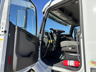 Volvo VHD64B300 cab interior and entry with open door showing steering wheel, driver seat, and floor area; fire extinguisher visible on the cab floor.