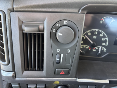 Dashboard and steering column of a Volvo VHD64B300 cab showing headlight dial, hazard button, climate vent, and instrument cluster.