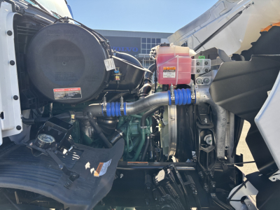 Volvo VHD64B300 truck engine bay showing coolant reservoir, hoses, air intake, and hydraulic components.
