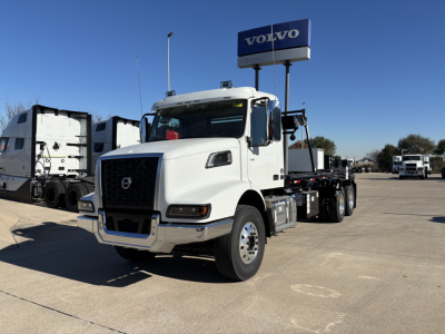 Volvo VHD64B300 truck in a dealership lot showing white cab and chassis with black grille and Volvo signage in background.