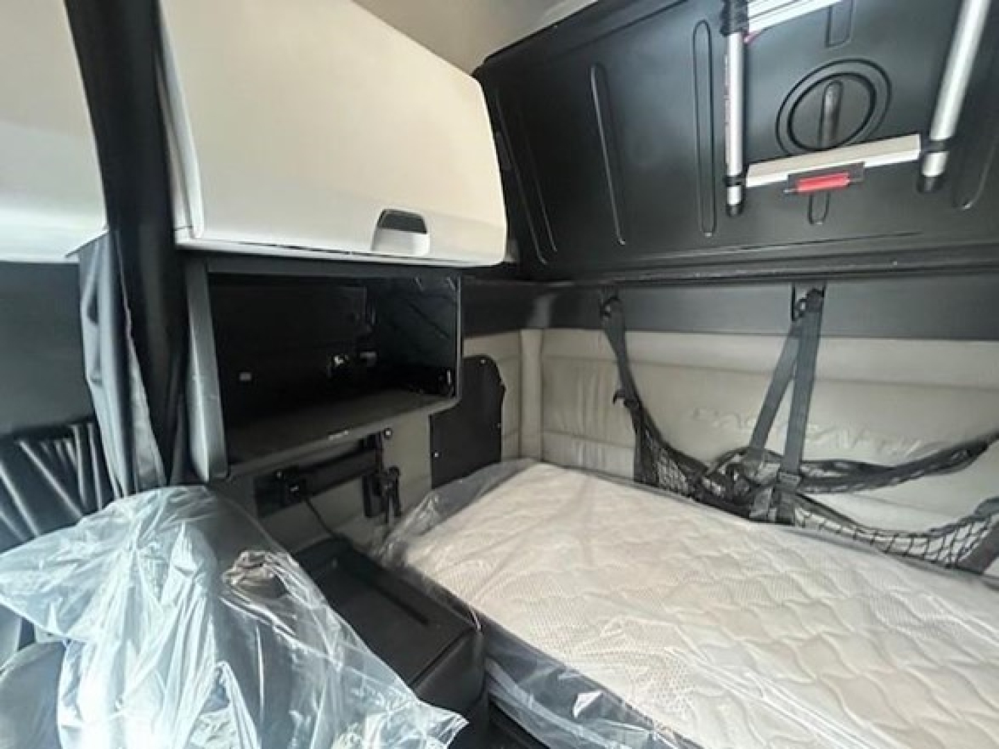Conventional sleeper truck cab interior with bunk bed and storage compartments visible.