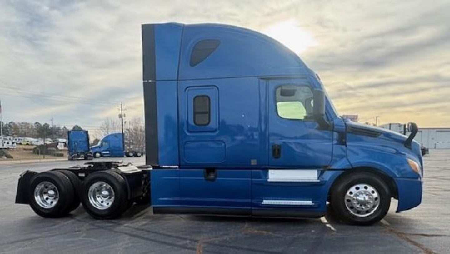  Freightliner Cascadia 126 side profile showing sleeper cab, blue paint, triple rear axles, chrome wheels, and exterior side mirrors.