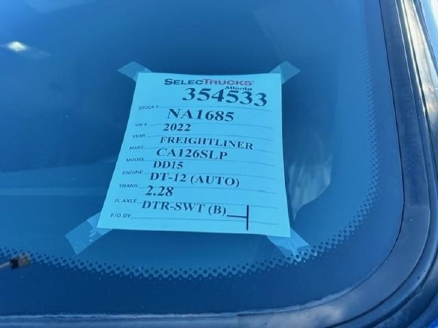 Sticker on windshield with stock number 354533, VIN NA1685, 2022 Freightliner Cascadia 126SLP, DD15 engine, 2.28 transmission?, DT-12 (AUTO).