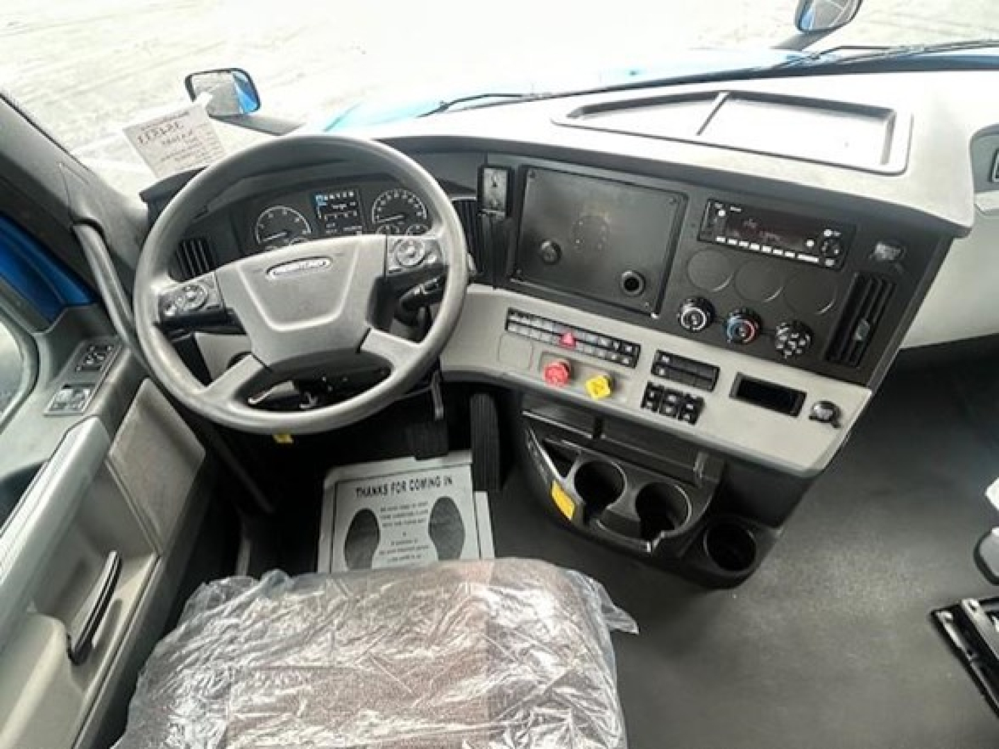 Truck cab interior showing steering wheel, dashboard with gauges, center console, and radio/display panel.