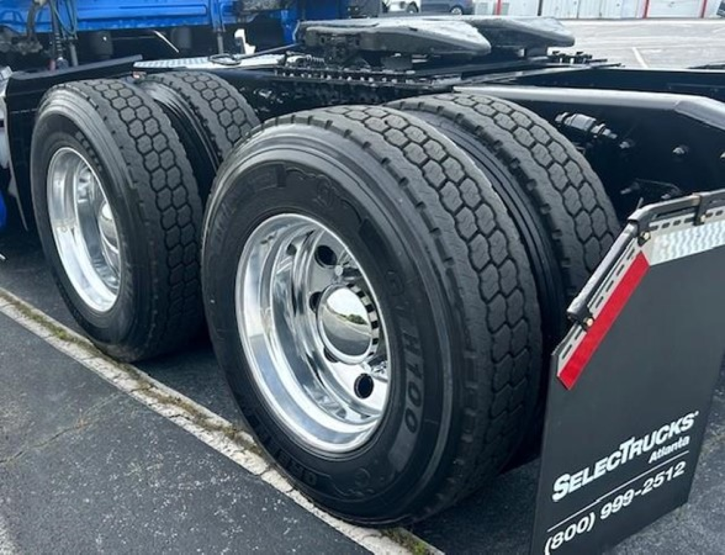 Rear triple-axle truck wheels with Goodyear tires, chrome rims, and a black mudguard showing Select Trucks Enterprises branding.