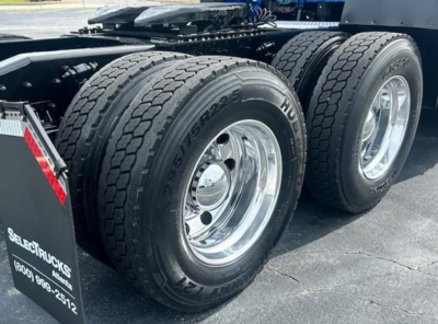 Dual rear Freightliner Cascadia drive tires and polished wheels on truck chassis showing tread pattern and rear fender area.